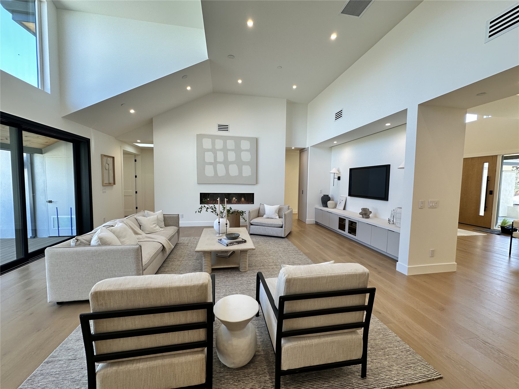 Living room with a vaulted ceiling, linear fireplace, and a built-in media wall.