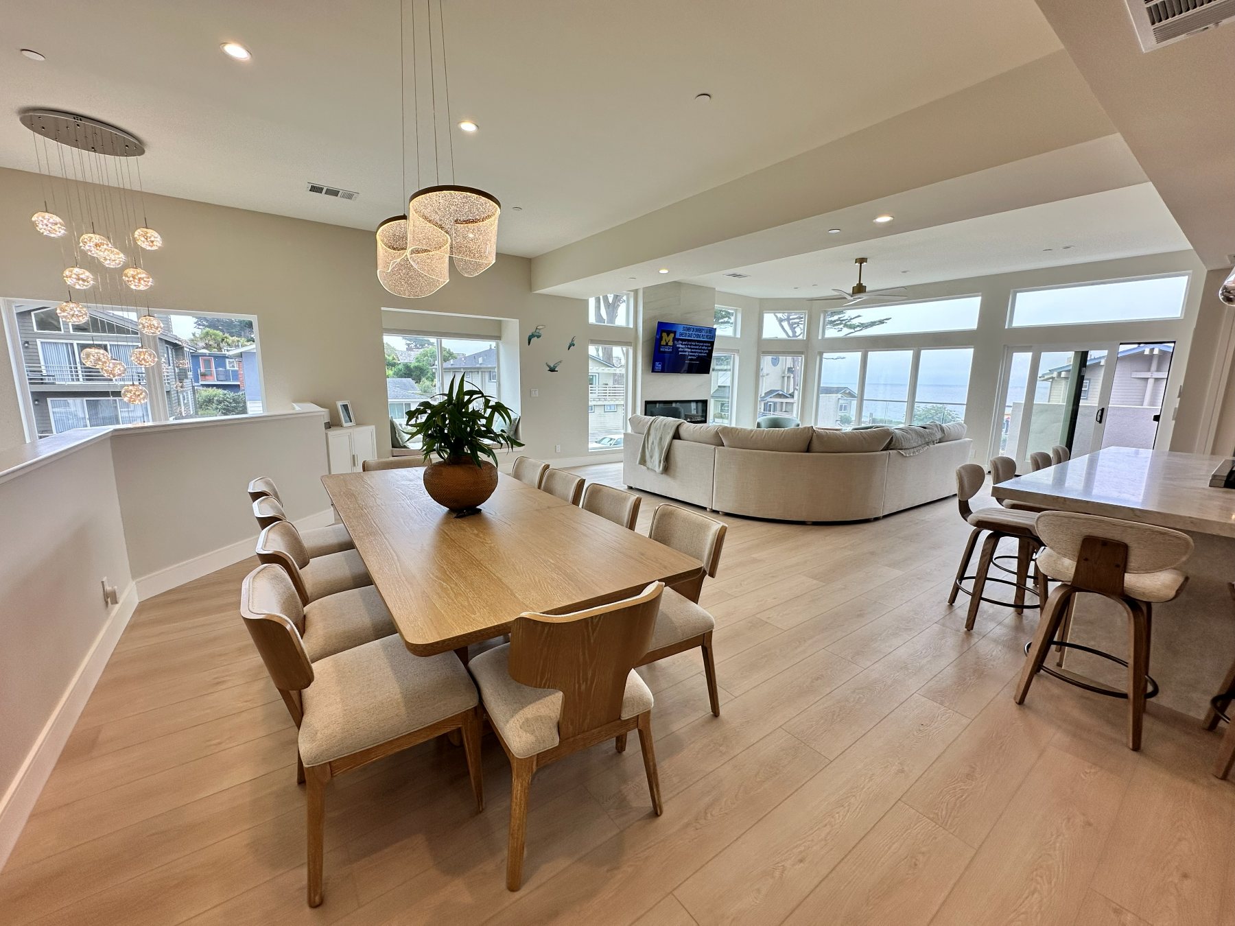 Dining area beneath a cluster of glass pendant lights, open to the kitchen and living room.