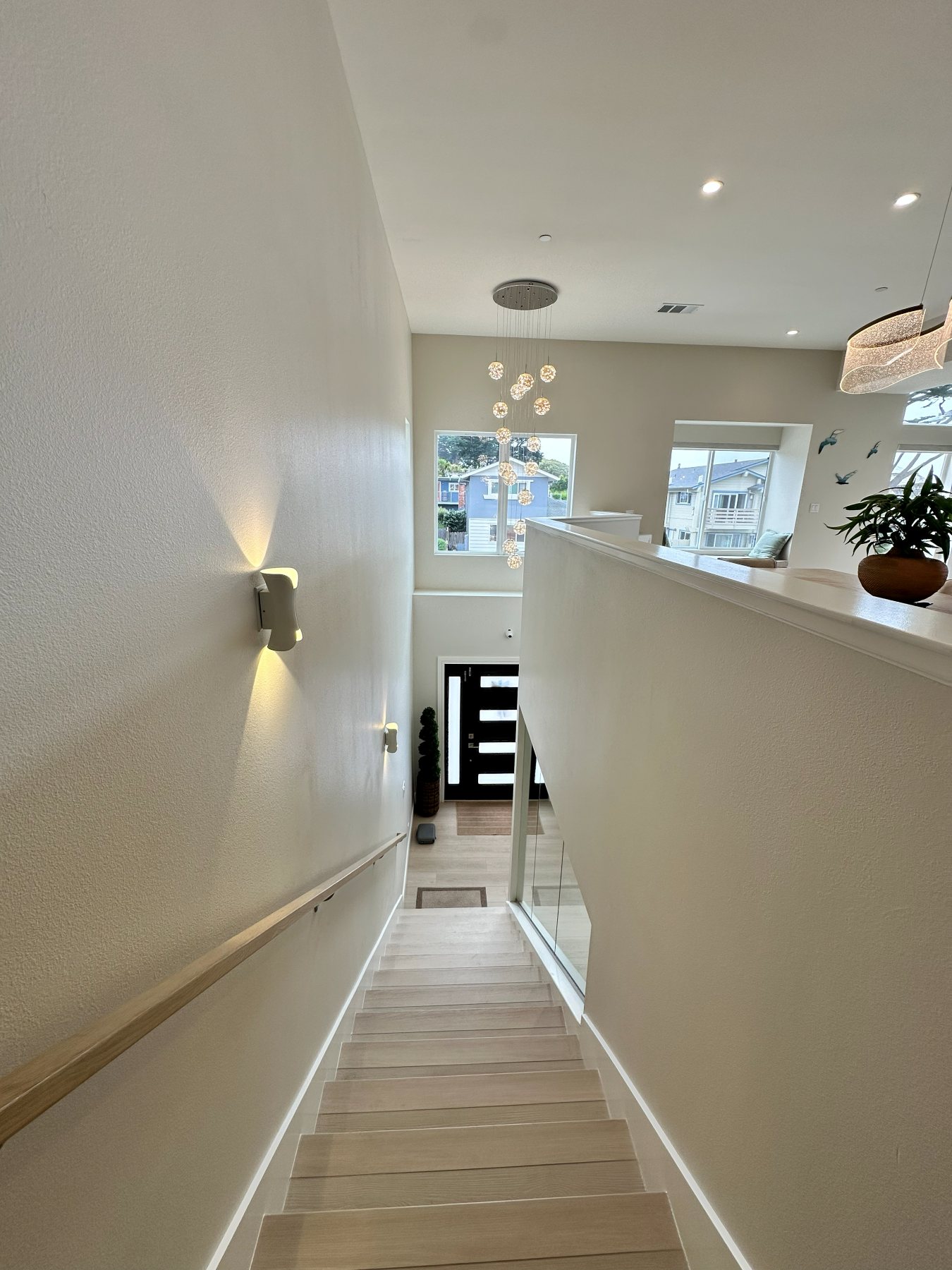 A stairwell landing with pendant lighting, descending toward the entry below.