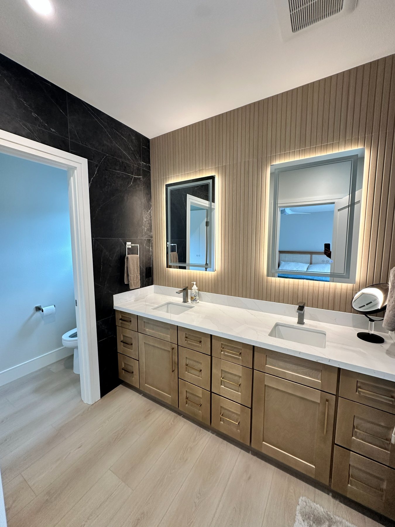 A bathroom with a ribbed wood accent wall, dual vanity, and a walk-in shower.