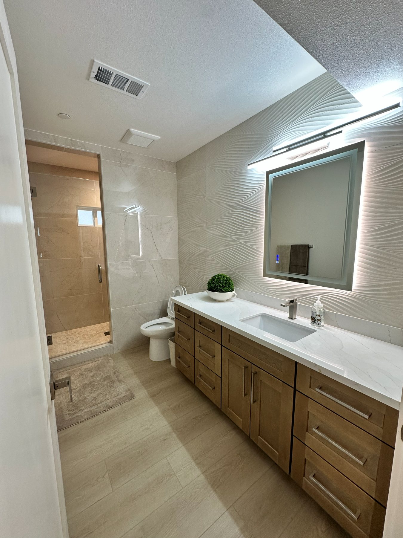 A bathroom finished in marble tile, with a glass-enclosed shower.