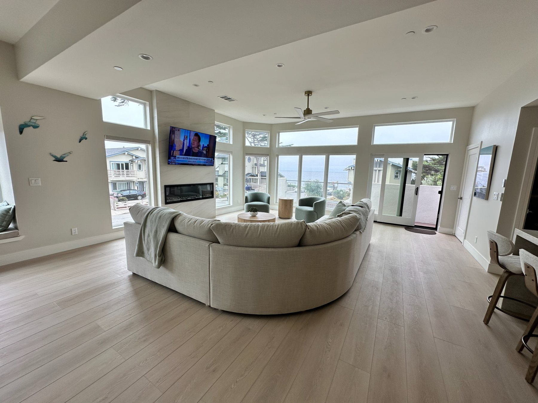 Living room with a curved sectional sofa and linear fireplace facing a wall of ocean-view windows.