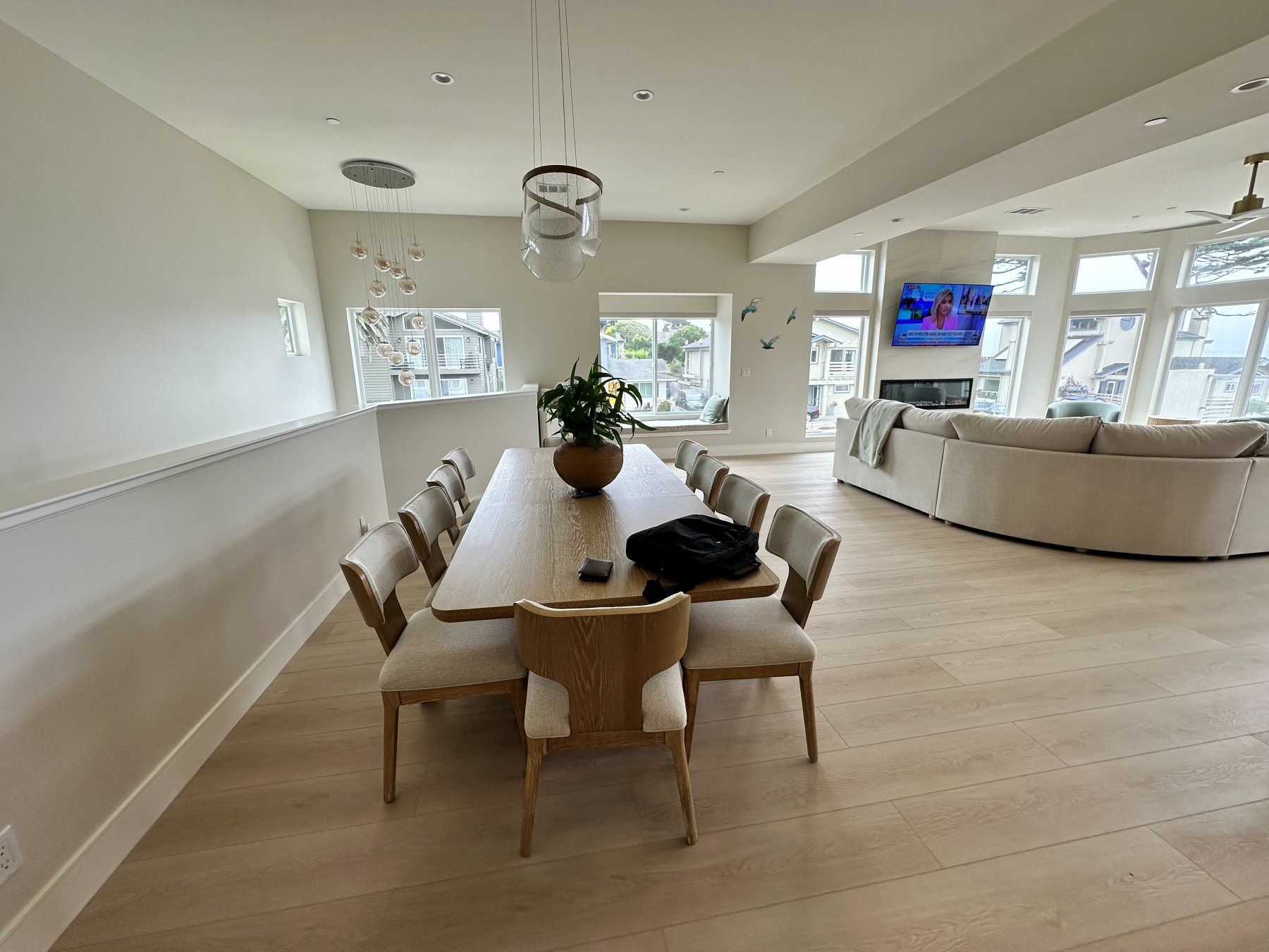 Dining table beneath a sculptural pendant light, open to the living room and kitchen beyond.