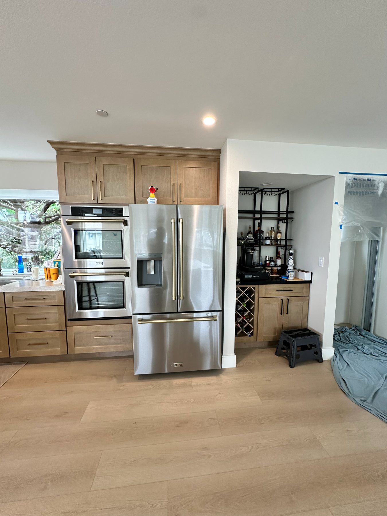 Built-in refrigerator and wall ovens beside an open-shelf wet bar with wine storage.