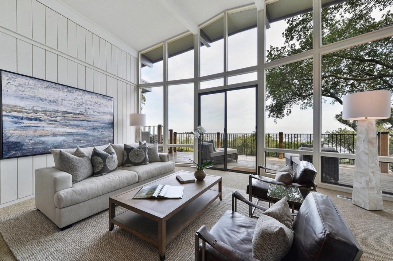 Great room addition with a wall of floor-to-ceiling windows opening onto a deck with hillside views.