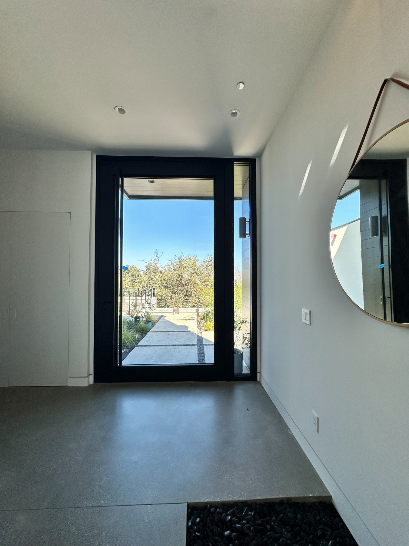 Entry with a black steel-framed glass door and a round mirror.