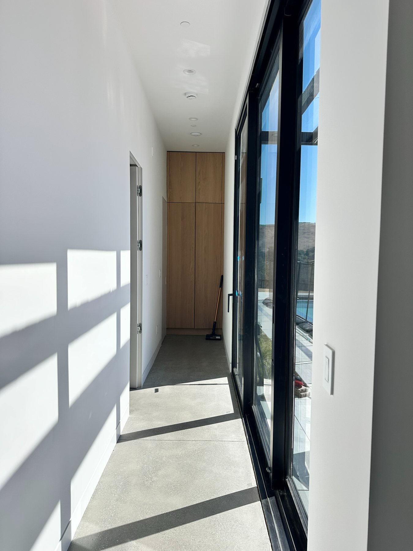 A hallway leading to the primary suite, with a glass door framing the hills beyond.