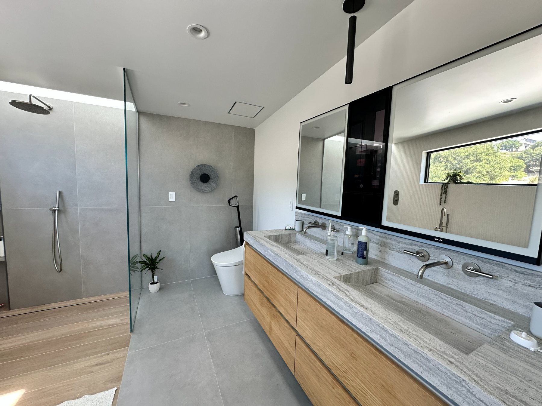 Primary bathroom with a double vanity, backlit mirrors, and a walk-in shower.