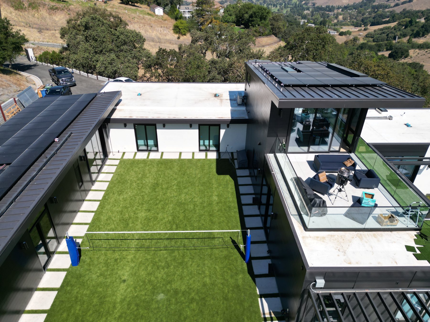 Aerial view of the turf backyard and rooftop deck, backed by the home's solar roof.