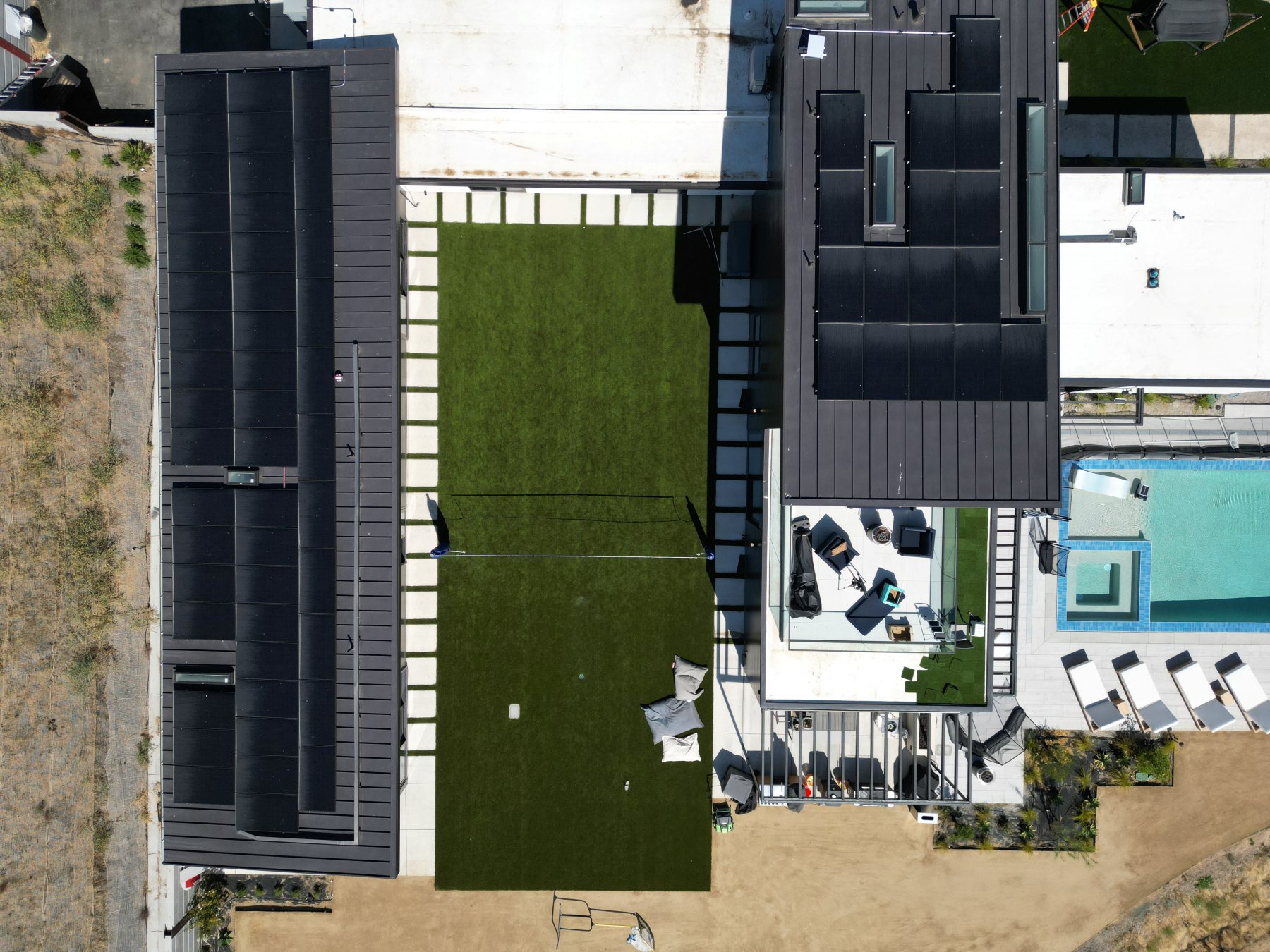 Overhead view of the turf yard, volleyball net, and rooftop lounge deck.