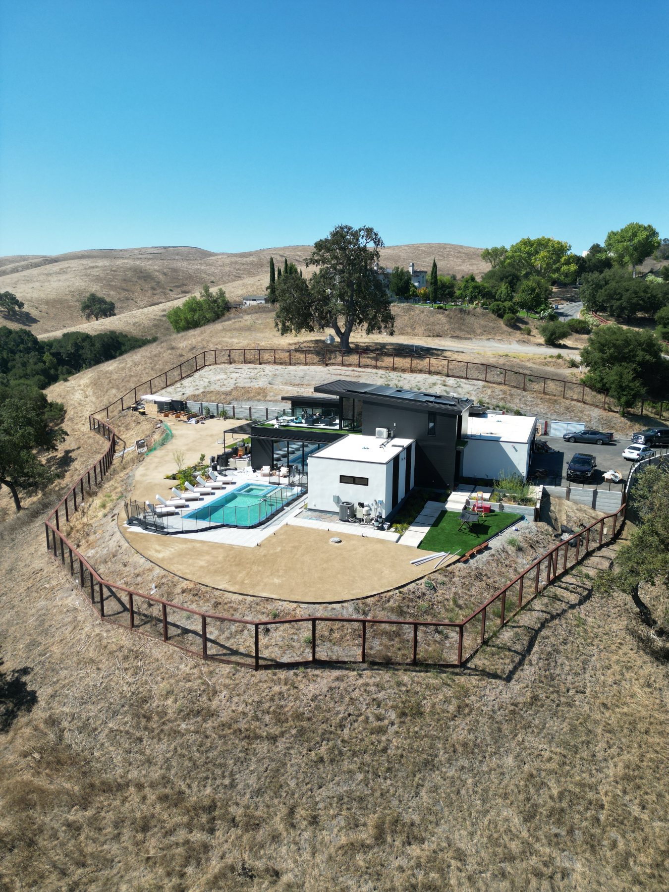 Aerial view of the fenced hillside lot, with the pool, motor court, and surrounding hills.