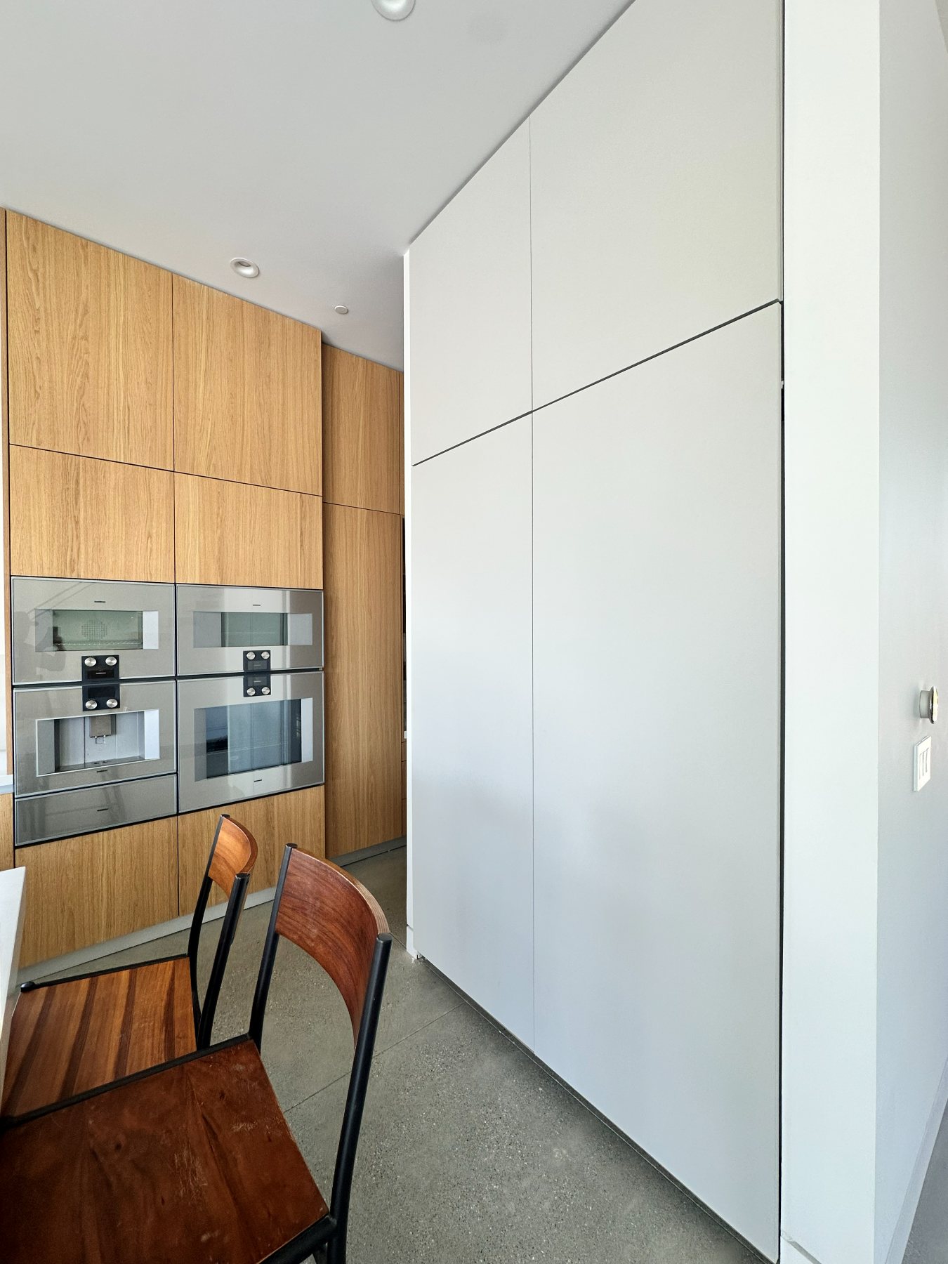 Kitchen wall ovens and built-in espresso machine, finished in wood cabinetry.
